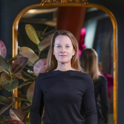 Porträtt av Hanna Mossfeldt, arbetsplatsstrateg, leende mot kameran mot en neutral bakgrund.