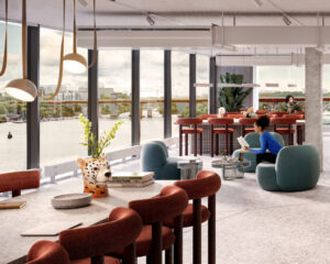 Alt-text (svenska): Ljus och modern kontorslounge med stora fönster från golv till tak och utsikt över vatten, grönområden och stadsmiljö. Rummet är inrett med mjuka fåtöljer i blå och roströda toner, runda soffbord och ett långt bord med stoppade stolar. Flera personer sitter och arbetar eller vistas i lokalen. Hängande taklampor, stora växter och dekorativa inredningsdetaljer skapar en varm och inbjudande miljö med fokus på samvaro och arbete.